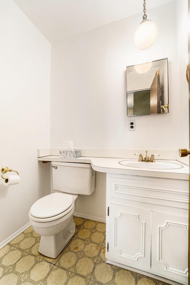 bathroom with toilet, vanity, and baseboards
