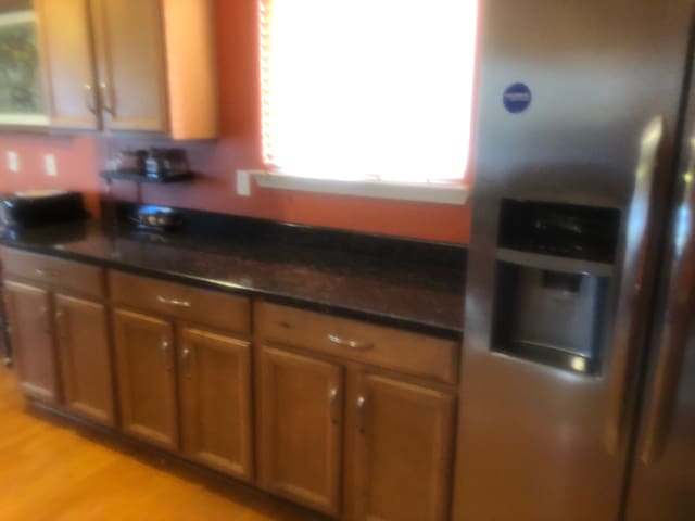 1130 Andover Cir, Commerce Twp, MI 48390 - kitchen featuring stainless steel fridge with ice dispenser, brown cabinets, dark countertops, and light wood-type flooring