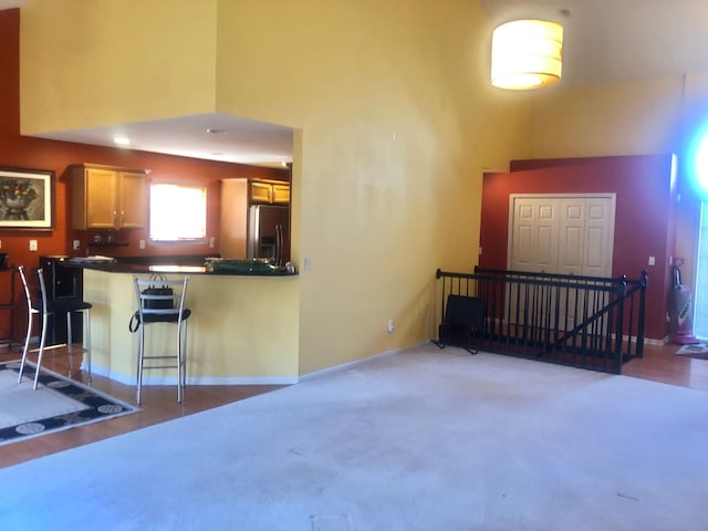 1130 Andover Cir, Commerce Twp, MI 48390 - kitchen featuring stainless steel fridge, a towering ceiling, a peninsula, baseboards, and dark countertops