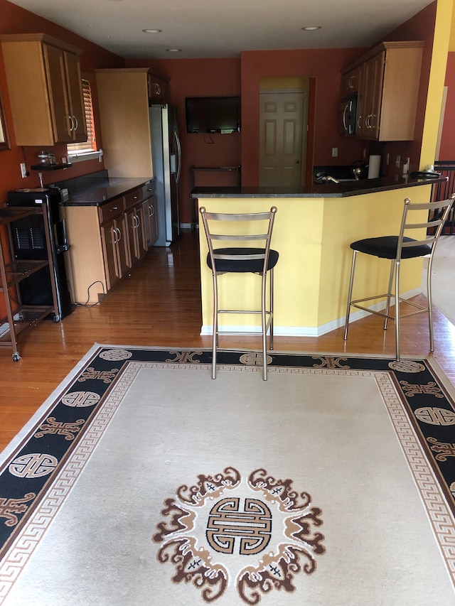 1130 Andover Cir, Commerce Twp, MI 48390 - kitchen with stainless steel appliances, dark countertops, dark wood-style flooring, a peninsula, and a breakfast bar area