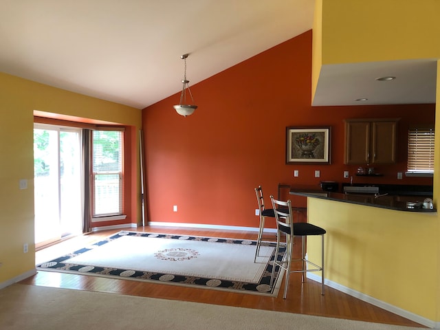 1130 Andover Cir, Commerce Twp, MI 48390 - kitchen featuring wood finished floors, dark countertops, high vaulted ceiling, baseboards, and decorative light fixtures