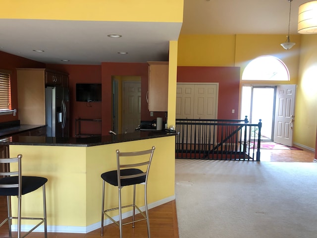 1130 Andover Cir, Commerce Twp, MI 48390 - kitchen with stainless steel refrigerator with ice dispenser, dark countertops, a kitchen bar, a peninsula, and recessed lighting