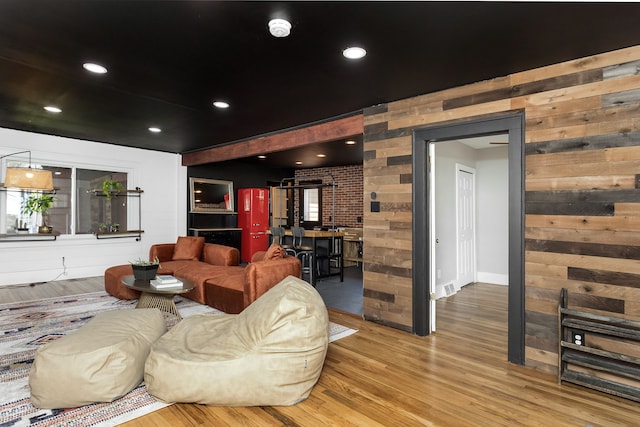 living area with wooden walls, visible vents, and wood finished floors