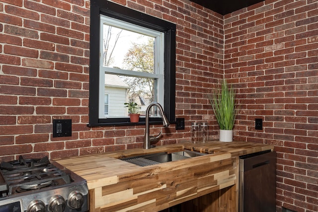 kitchen featuring a sink, wood counters, and brick wall