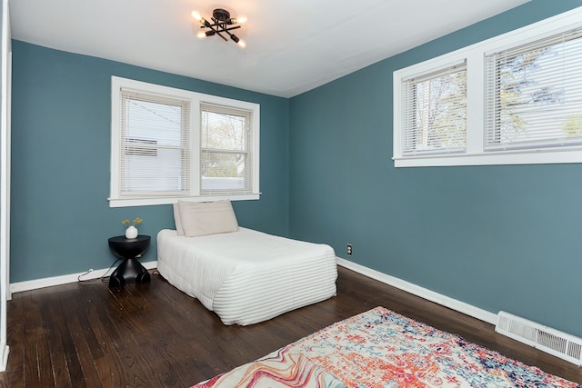 bedroom with baseboards, visible vents, and wood finished floors