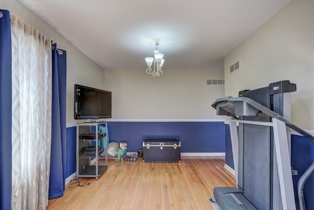 exercise room with a chandelier, baseboards, visible vents, and hardwood / wood-style flooring