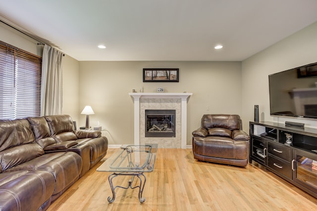 living area with light wood-style floors, recessed lighting, and a tiled fireplace