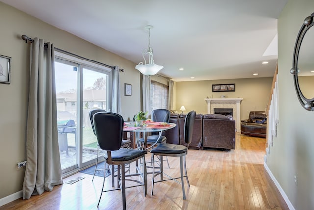 dining room featuring a fireplace, light wood-style flooring, recessed lighting, baseboards, and visible vents