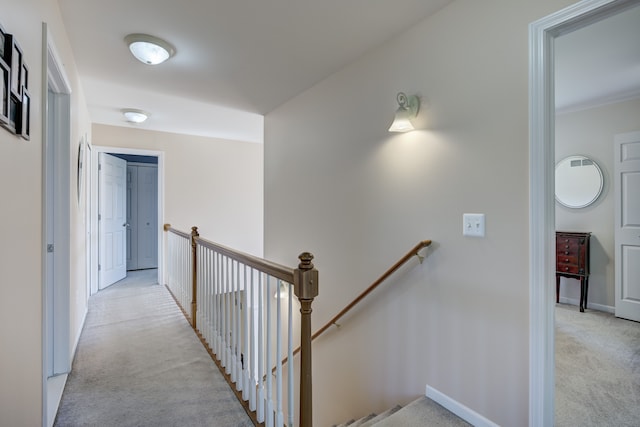 corridor with light colored carpet, baseboards, and an upstairs landing