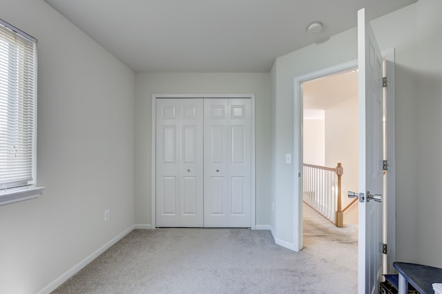 unfurnished bedroom with carpet floors, baseboards, multiple windows, and a closet