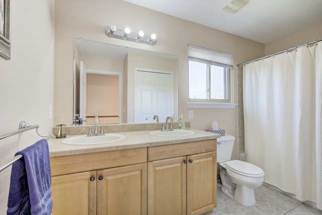 full bathroom with double vanity, a sink, tile patterned flooring, and toilet