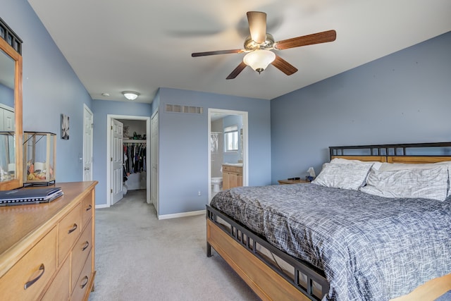 bedroom featuring light carpet, a walk in closet, baseboards, visible vents, and a closet