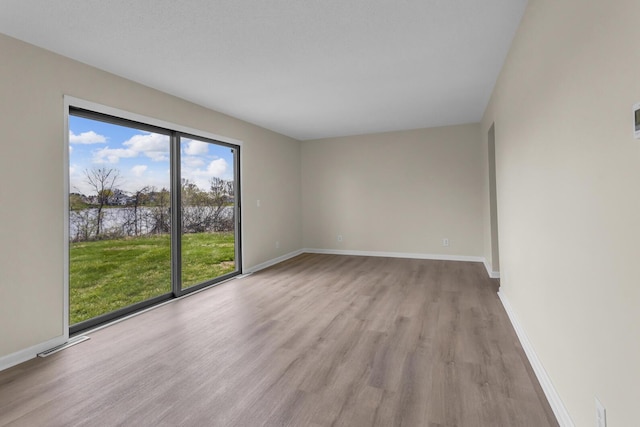 9315 Kingsley Dr, Onsted, MI 49265 - spare room with light wood finished floors, visible vents, a water view, and baseboards