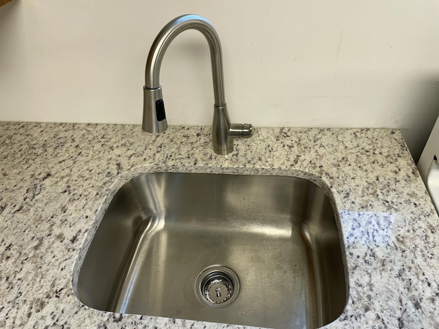 room details featuring light stone counters and a sink
