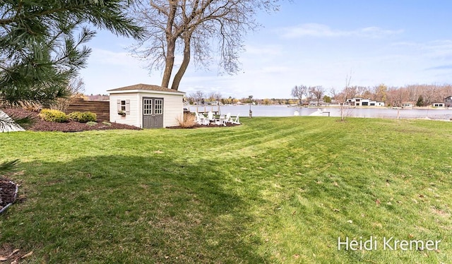 view of yard featuring an outdoor structure, a water view, and fence