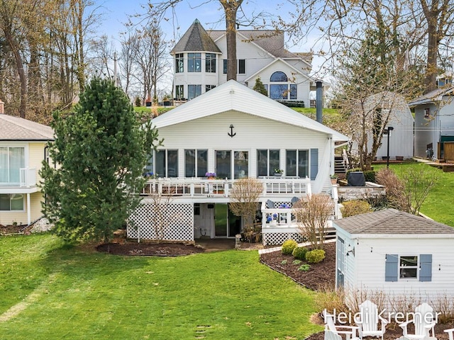 back of property with a lawn, an outdoor structure, a wooden deck, and a sunroom