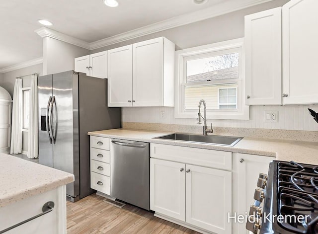 kitchen featuring ornamental molding, a sink, white cabinets, and stainless steel appliances