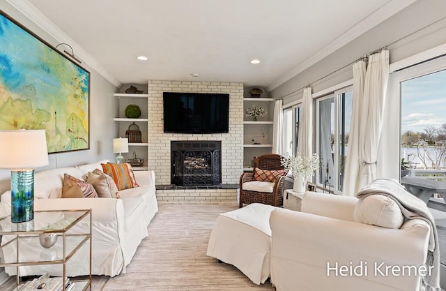 living area with light wood-type flooring, a healthy amount of sunlight, crown molding, and a brick fireplace