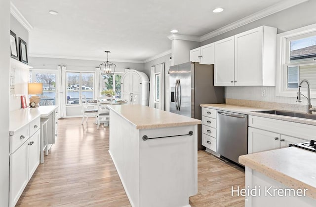 kitchen featuring dishwasher, white cabinets, a kitchen island, and a sink