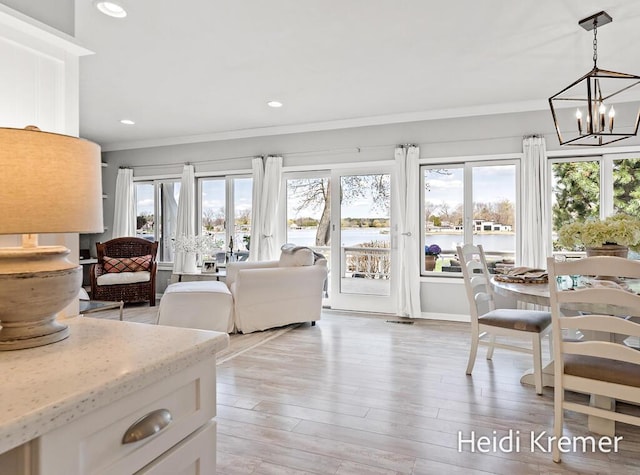 living room featuring recessed lighting, ornamental molding, a notable chandelier, and light wood-style floors