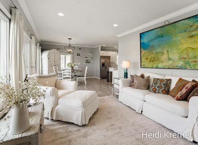 living area featuring recessed lighting, ornamental molding, light wood finished floors, baseboards, and a notable chandelier