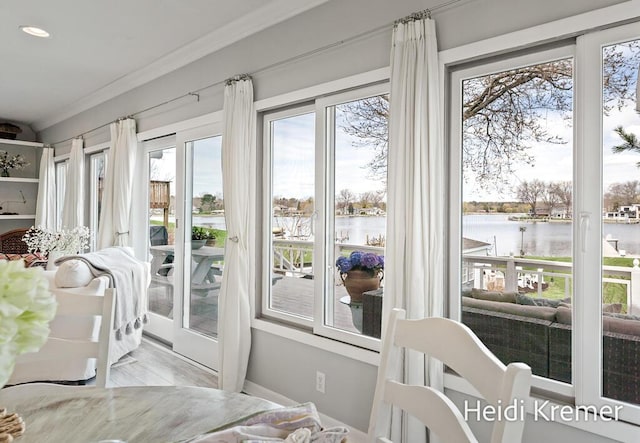 sunroom featuring a wealth of natural light, recessed lighting, ornamental molding, and a water view