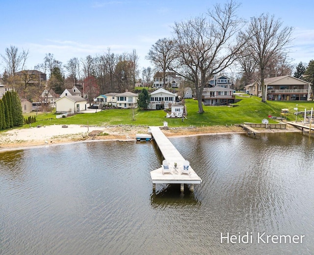 view of dock with a lawn, a water view, and a residential view