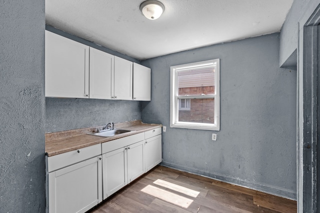 15374 Birwood St, Detroit, MI 48238 - kitchen featuring wood finished floors, light countertops, white cabinets, a sink, and baseboards