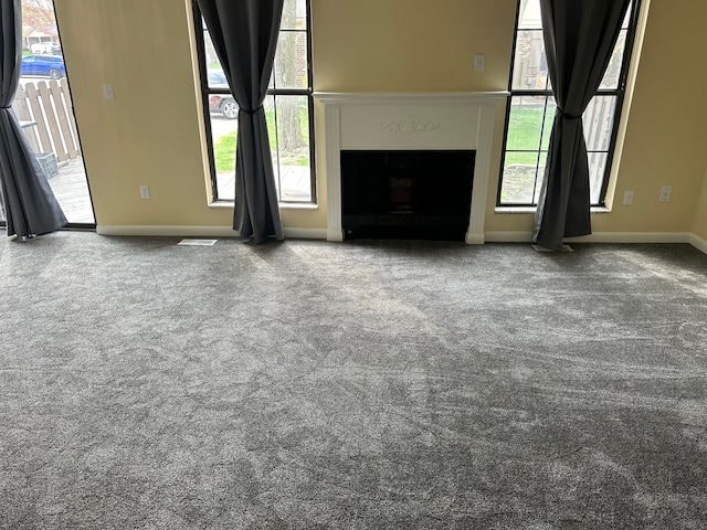 unfurnished living room with carpet flooring, plenty of natural light, and a fireplace