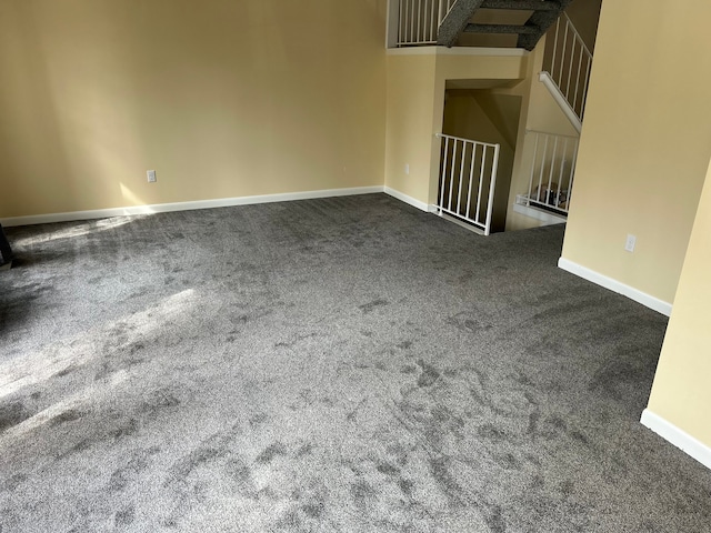 empty room featuring baseboards and dark colored carpet