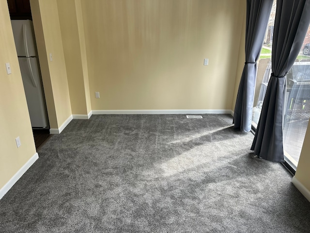 unfurnished room featuring baseboards, visible vents, and dark carpet