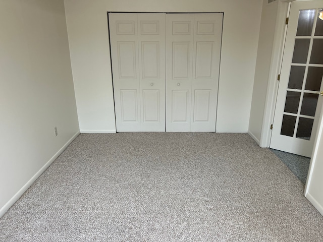 unfurnished bedroom featuring carpet floors, baseboards, and a closet
