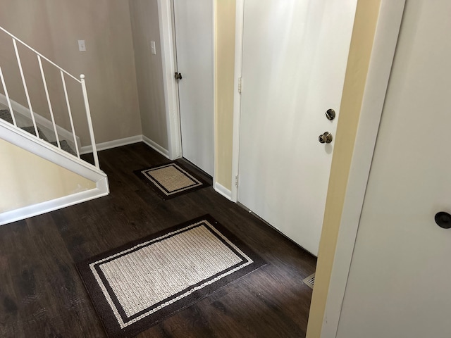entrance foyer with baseboards, wood finished floors, and stairway