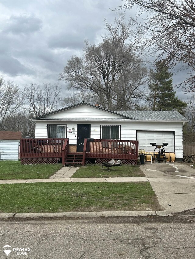 1934 Basil Ln, Flint, MI 48504 - view of front facade featuring concrete driveway, an attached garage, a wooden deck, and a front lawn