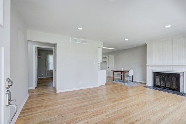 unfurnished living room featuring visible vents, a fireplace, light wood-style floors, baseboards, and recessed lighting