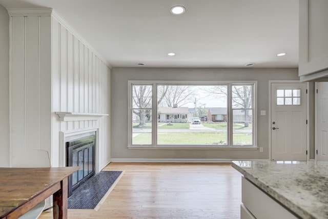 unfurnished living room featuring light wood-type flooring, a fireplace with flush hearth, baseboards, and recessed lighting