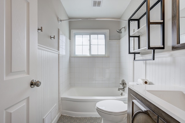 bathroom with toilet, visible vents, tub / shower combination, and a wainscoted wall