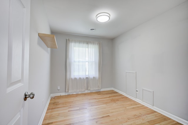 unfurnished room featuring baseboards, visible vents, and wood finished floors