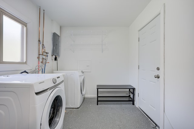 washroom with electric panel, baseboards, laundry area, and washing machine and clothes dryer