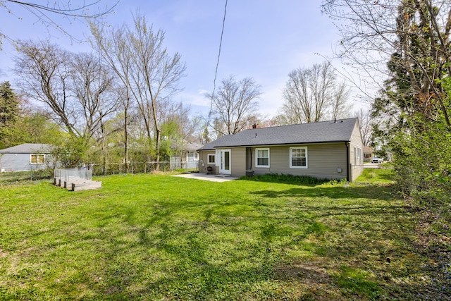 back of house featuring fence, roof with shingles, a chimney, a patio area, and a lawn