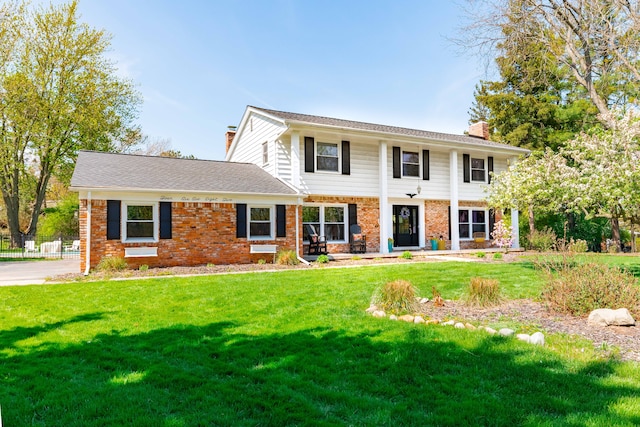 view of front facade with a chimney, a front lawn, and brick siding