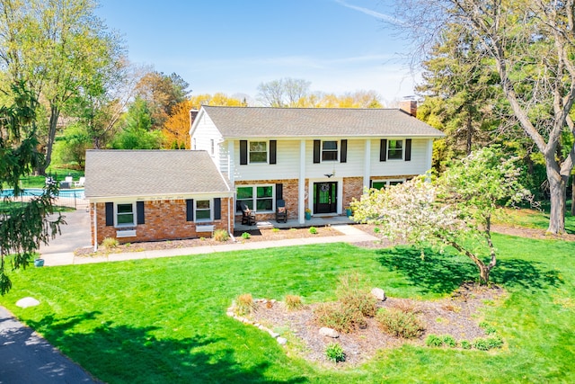 view of front of home with brick siding, a front lawn, and a chimney