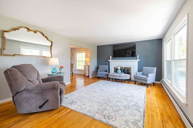 living room with light wood-style floors, baseboards, a fireplace, and a baseboard heating unit