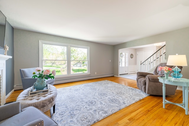 living room featuring stairway, a baseboard radiator, and wood finished floors