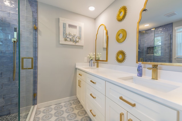 bathroom with double vanity, visible vents, a shower stall, a sink, and baseboards