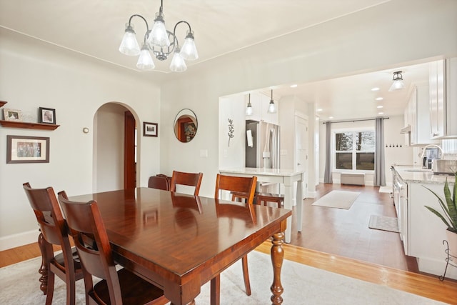 1743 Midland Rd, Bay City, MI 48706 - dining area with arched walkways, light wood-type flooring, a chandelier, and baseboards