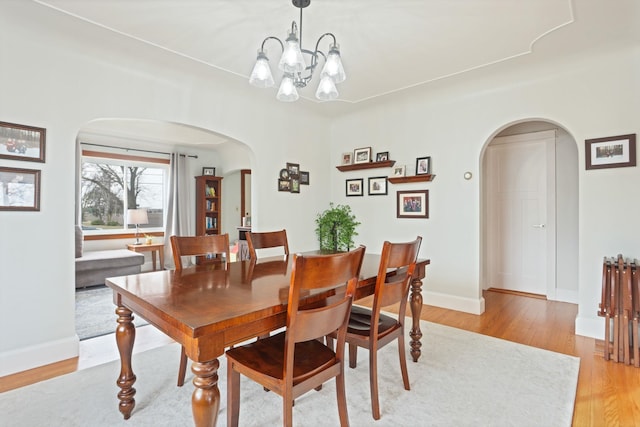 1743 Midland Rd, Bay City, MI 48706 - dining area with arched walkways, light wood-style flooring, baseboards, and a chandelier