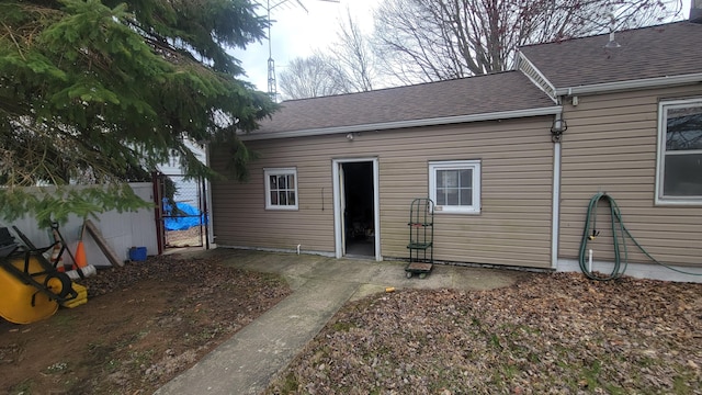 back of house featuring a gate, fence, and a shingled roof