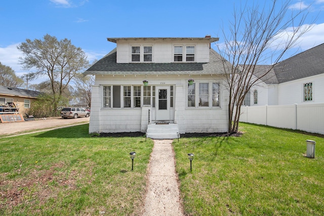 bungalow-style house featuring fence, roof with shingles, and a front lawn