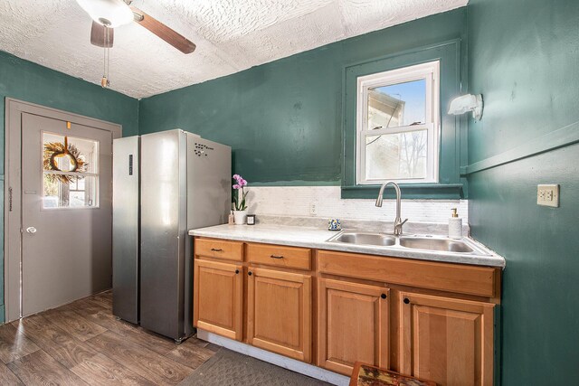 kitchen with freestanding refrigerator, a sink, dark wood-style flooring, a textured ceiling, and a ceiling fan
